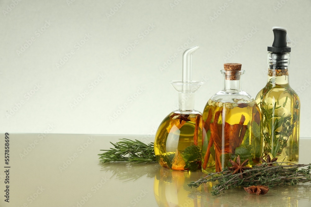Cooking oil with different spices and herbs in bottles on beige table. Space for text Cooking oil with different spices and herbs in bottles on beige table. Space for text