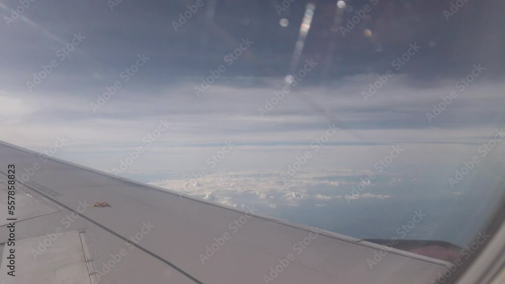 view of sky from inside airplane cabin while flying over cloud sky scape through the window with wing view view of sky from inside airplane cabin while flying over cloud sky scape through the window with wing view
