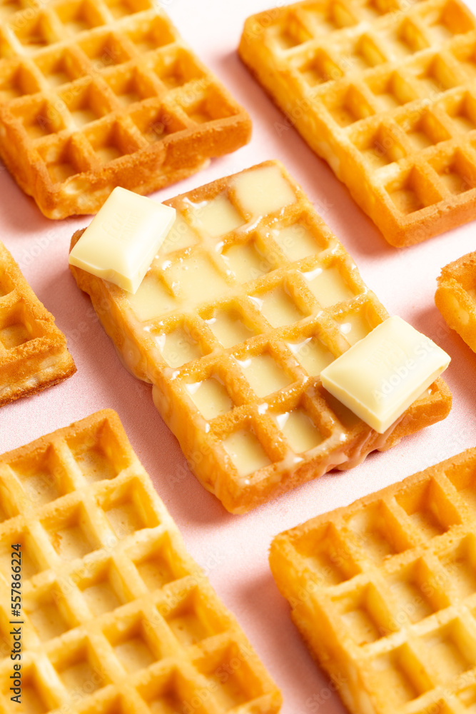 Diagonal vertical view of belgian waffles with white chocolate on a pink background Diagonal vertical view of belgian waffles with white chocolate on a pink background