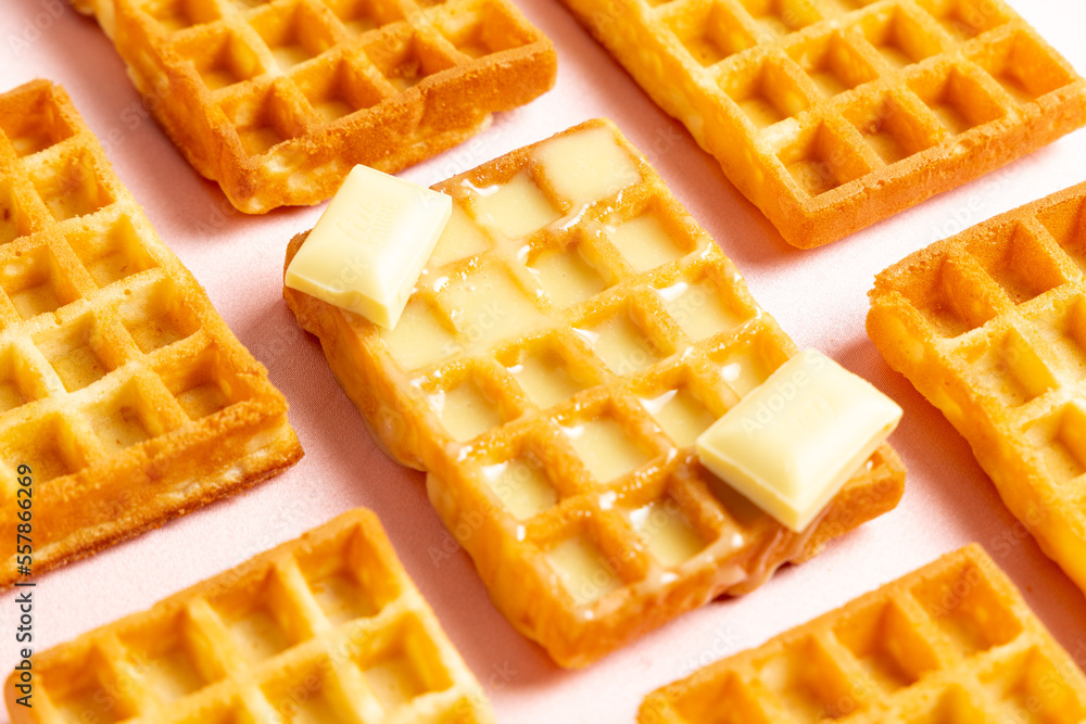 Diagonal close up view of belgian waffles with white chocolate on a pink background Diagonal close up view of belgian waffles with white chocolate on a pink background