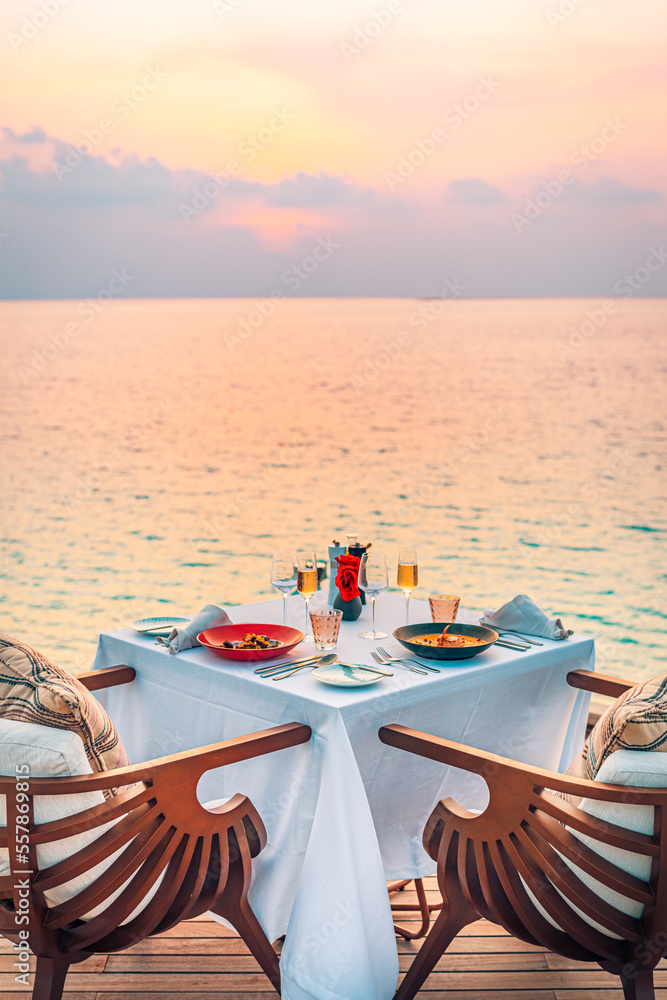 Seascape view under sunset light with dining table with infinity pool around. Romantic tranquil getaway for two, couple concept. Chairs, food and romance. Luxury destination dining, honeymoon template