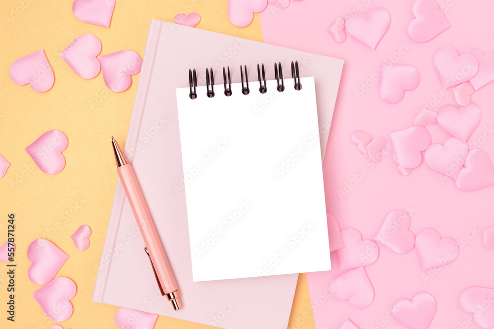 Blank notepad, pen and textile hearts confetti on a pink and gold background. Festive composition. Blank notepad, pen and textile hearts confetti on a pink and gold background. Festive composition.