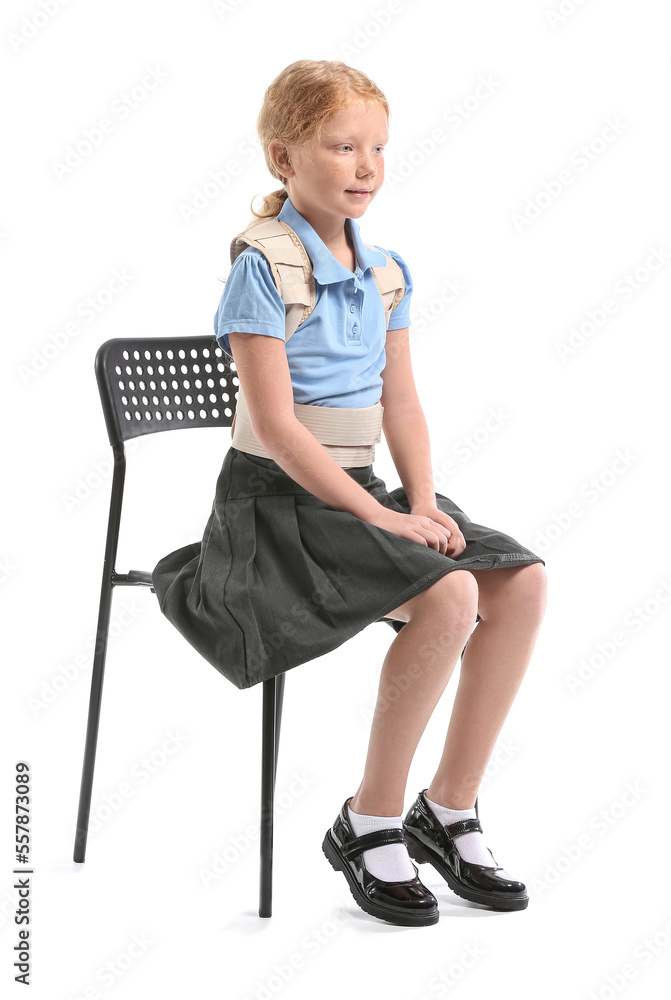 Fototapeta premium Little schoolgirl in back brace sitting on white background