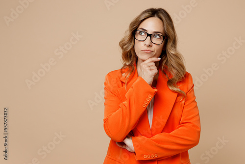 Konstfotografi Young successful employee business woman corporate lawyer 30s wears classic formal orange suit glasses work in office prop up chin look aside on area isolated on plain beige color background studio