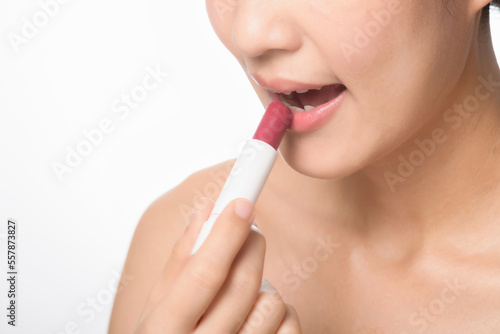 Beautiful portrait young asian woman looking mirror applying makeup lipstick at room. clipping path