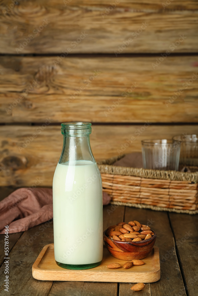 Board with bottle of almond milk and nuts on wooden table Board with bottle of almond milk and nuts on wooden table