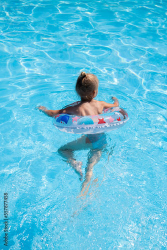 Child girl learn to swim with an inflatable ring in the pool © Alex