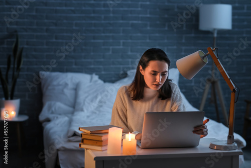 Young woman using laptop at home during blackout photo