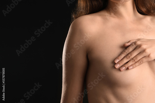 Naked young woman on black background. Breast cancer awareness concept