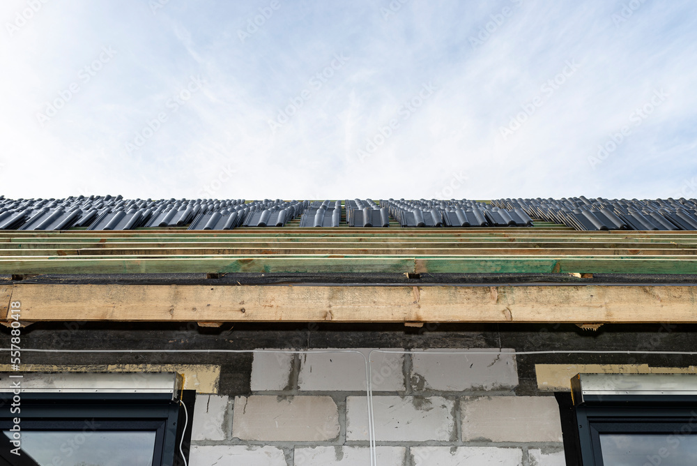 Roof ceramic tile arranged in packets on the roof on roof battens. Preparation for laying tiles on a boarded roof. Roof ceramic tile arranged in packets on the roof on roof battens. Preparation for laying tiles on a boarded roof.