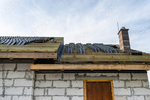 Roof ceramic tile arranged in packets on the roof on roof battens. Preparation for laying tiles on a boarded roof.