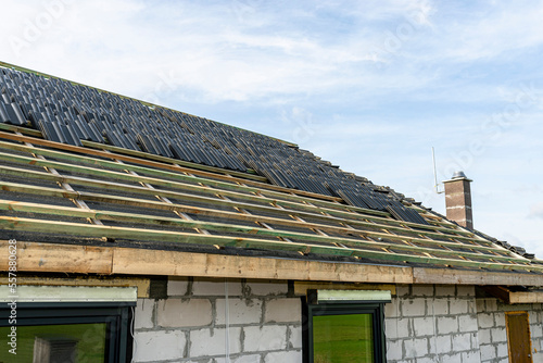 Roof ceramic tile arranged in packets on the roof on roof battens. Preparation for laying tiles on a boarded roof.