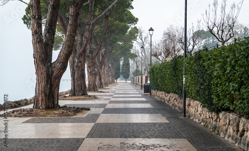 Garda lake  waterfront of the picturesque town of Lazise on Lake Garda in the winter season. Lazise, Verona province, northern Italy - January 21, 2022 photo