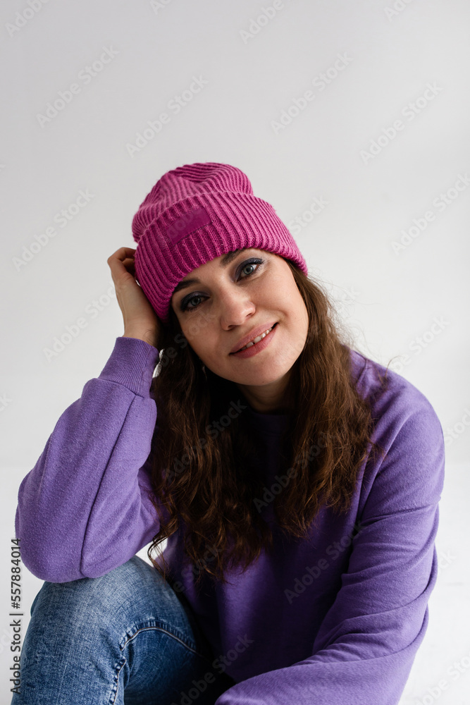 Beautiful young woman in purple hat and sweatshirt on gray background in studio Beautiful young woman in purple hat and sweatshirt on gray background in studio