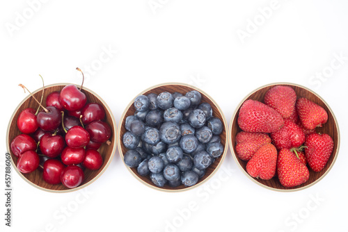 Blueberries, strawberries and cherry in bowls on white