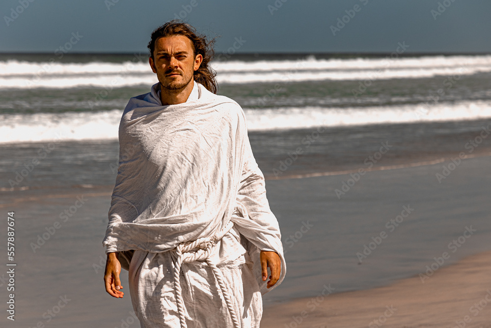Portrait of a handsome, holy, bearded man in flowing white robes next to sea
