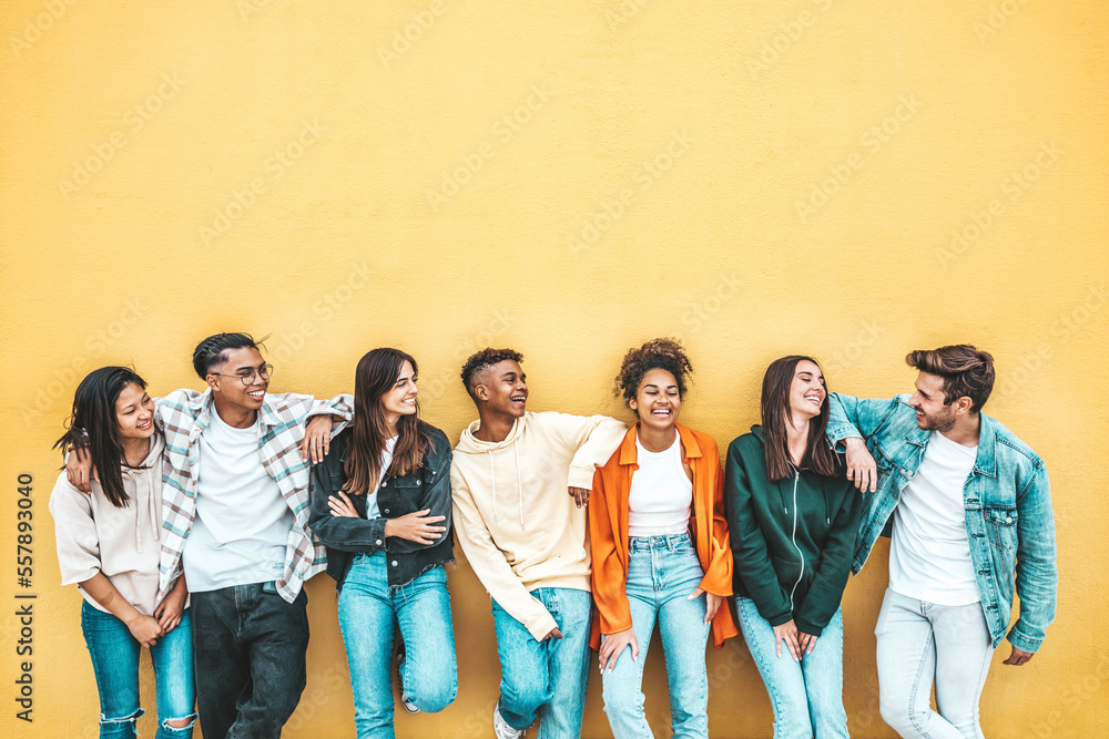 Happy multiracial friends standing over isolated background - Cheerful young people socializing outdoors - University students laughing together on yellow wall - Youth culture and friendship concept - obrazy, fototapety, plakaty 