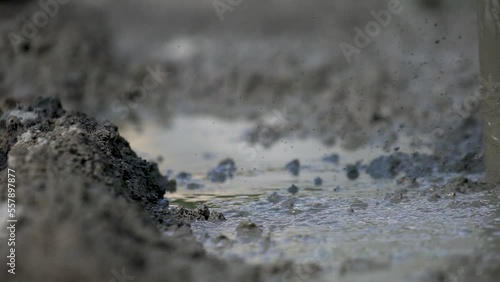 Worker using power tool, vibrator, compactor, for compacting fresh liquid concrete in close up slow motion view.