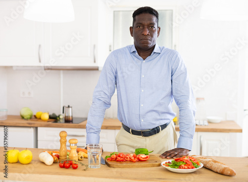 African american man preparing vegetable salad in kitchen