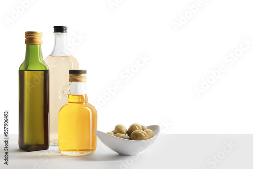 Bottles of different cooking oils and olives on white background, space for text