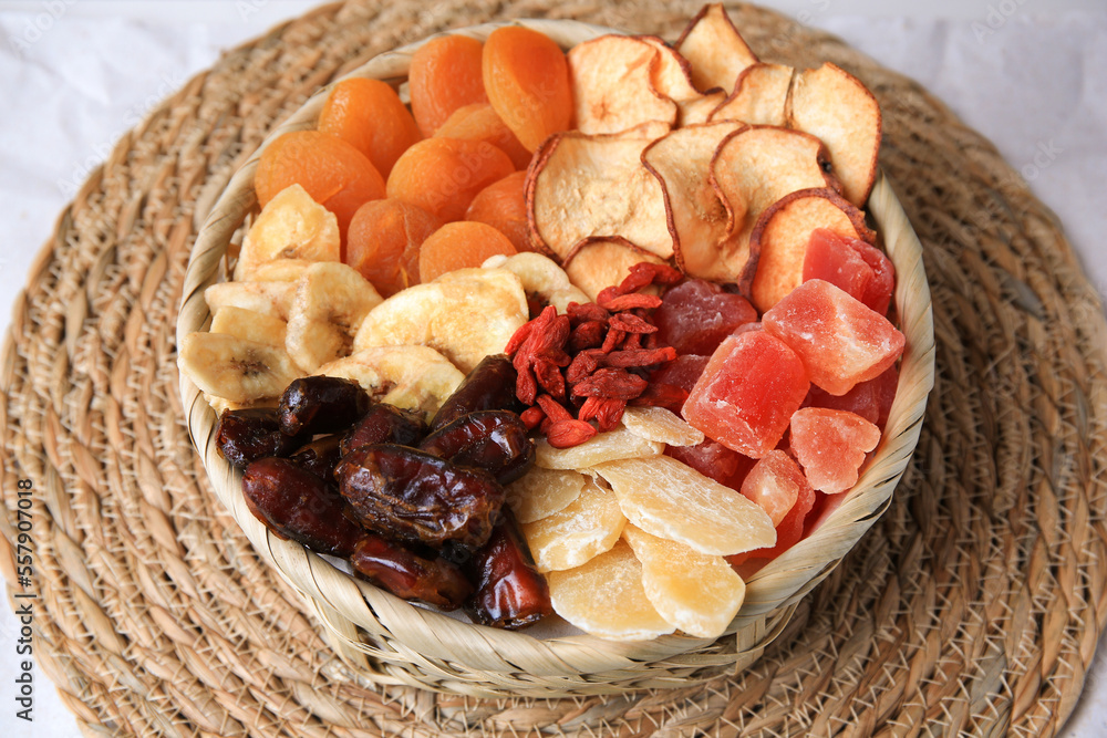 Wicker basket with different dried fruit on mat Wicker basket with different dried fruit on mat