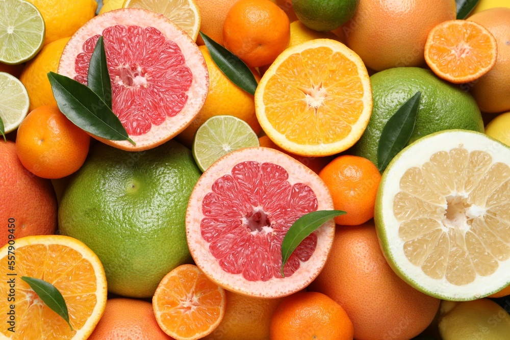 Different ripe citrus fruits with green leaves as background, top view Different ripe citrus fruits with green leaves as background, top view