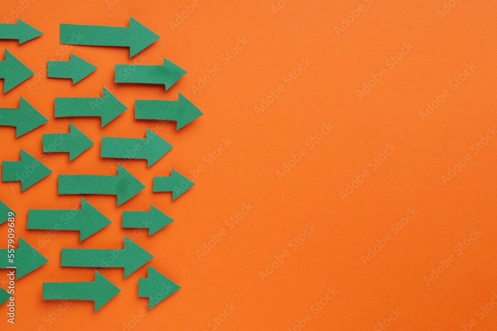 Paper arrows on orange background, flat lay. Space for text Paper arrows on orange background, flat lay. Space for text