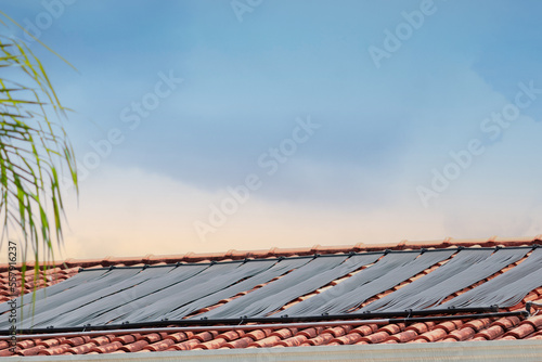 Water Heating System on the Roof of the House in a Sunny and Cloudy Day. photo