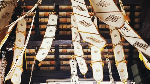 Many white ribbons with gold ornaments flutter in the wind in a Buddhist temple in Southeast Asia. Buddhist symbols Tung Lanna style decorations.