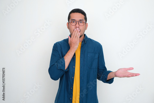 Adult Asian man cover his mouth with one hand and showing shocked expression photo