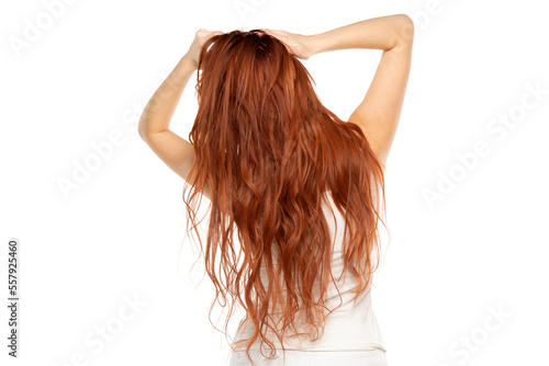 Back view of redhead woman with long ginger wavy hair on a white background