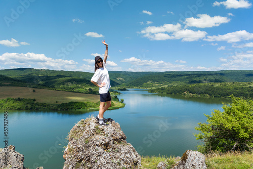 Young traveler woman standing on a rocks above blue lake .Traveling in the summer nature in Bulgaria	. Pchelina Lake  photo