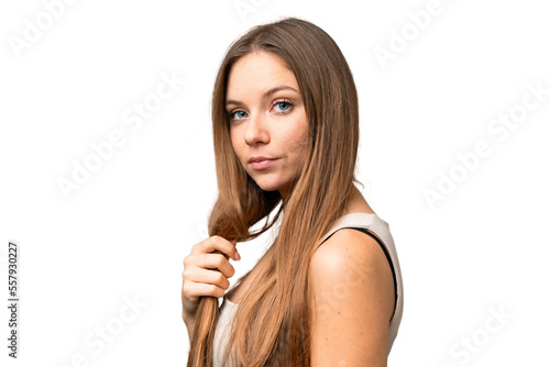 Young blonde woman over isolated chroma key background touching her hair. Close up portrait