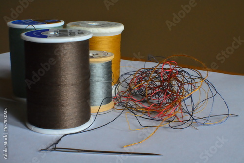 Foto four spools of thread with needle and tangled strands
