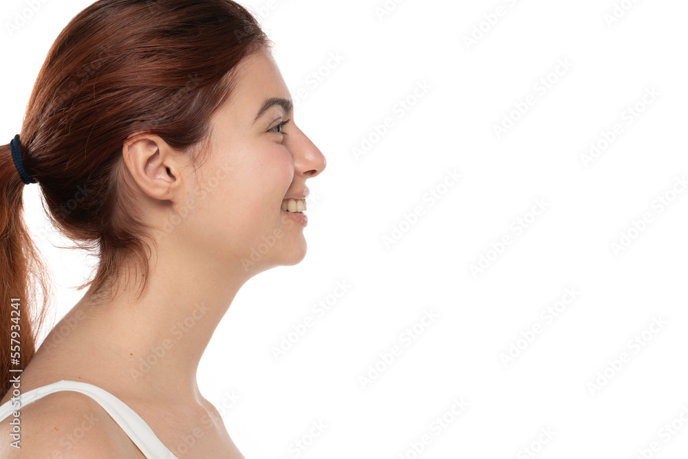 profile of a young smiling redhead woman without makeup with long hair on a white studio background profile of a young smiling redhead woman without makeup with long hair on a white studio background