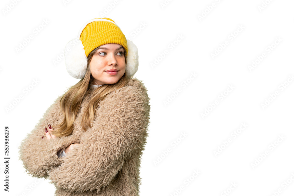 Young girl wearing winter muffs over isolated chroma key background with arms crossed and happy