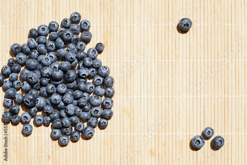 Food background. Ripe blueberries scattered on natural wooden tablecloth.