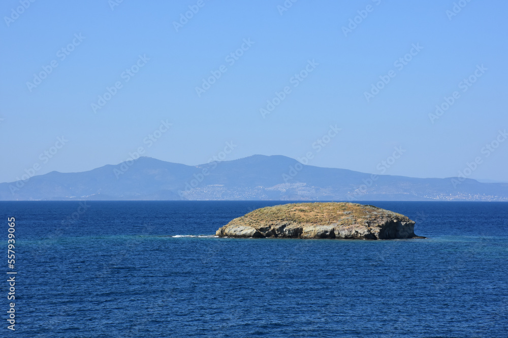 A Small islet, cliffs, mountain and bay view in the virgin bays of İzmir Foça. Virgin coves of the Aegean Sea. Phokaia, Izmir Bays.The view of the Karaburun mountains and the Aegean Gulf from Foça.