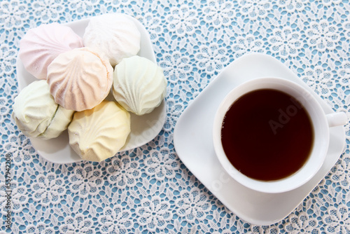 Traditional delicious brewed tea in a cup and air marshmallows lie on table, a sweet dessert. Tea party time.