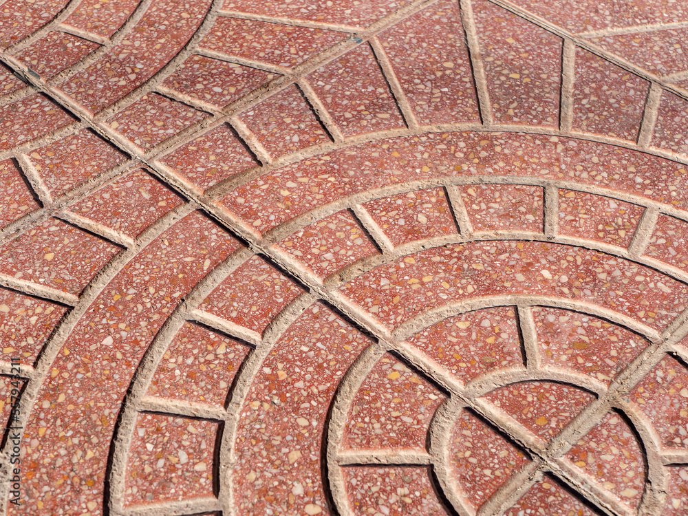 Diagonal view on a rounded pattern on a red stone pavement