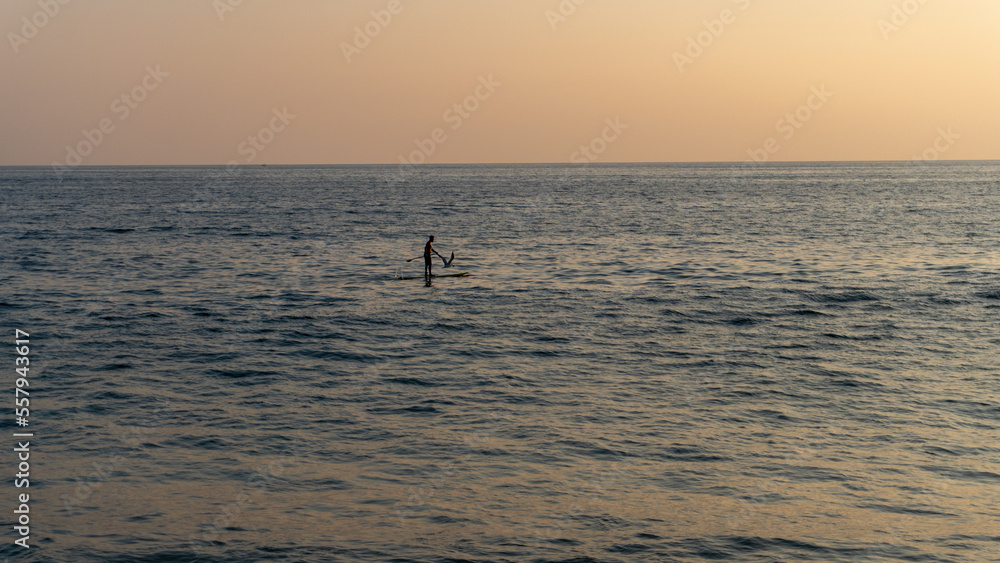 person on surfboard in the middle of the sea at sunset in huatulco beach oaxaca, mexico