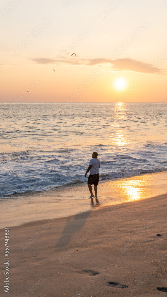 Young man walking on the shore of the beach in costas de oaxaca at sunset Young man walking on the shore of the beach in costas de oaxaca at sunset