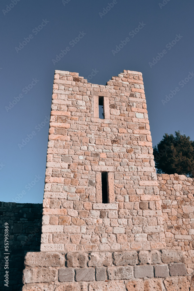 Detailed stone walls of a ruined old medieval castle and a clear sky behind it