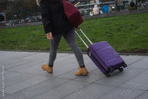 closeup of woman walking  in the street with suitcase near the train station