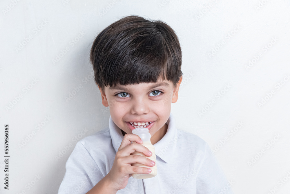Cute boy in white shirt on white background - drinking fermented milk Cute boy in white shirt on white background - drinking fermented milk