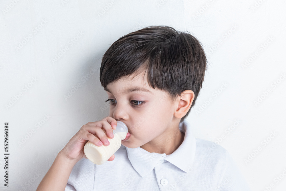 Cute boy in white shirt on white background - drinking fermented milk Cute boy in white shirt on white background - drinking fermented milk