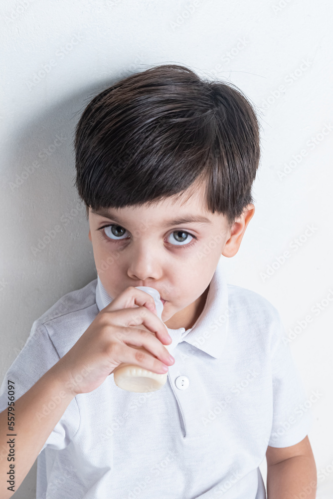 Cute boy in white shirt on white background - drinking fermented milk Cute boy in white shirt on white background - drinking fermented milk