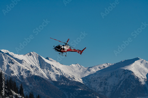 Tableau sur toile A helicopter taken in flight in front of a snowy mountain panorama