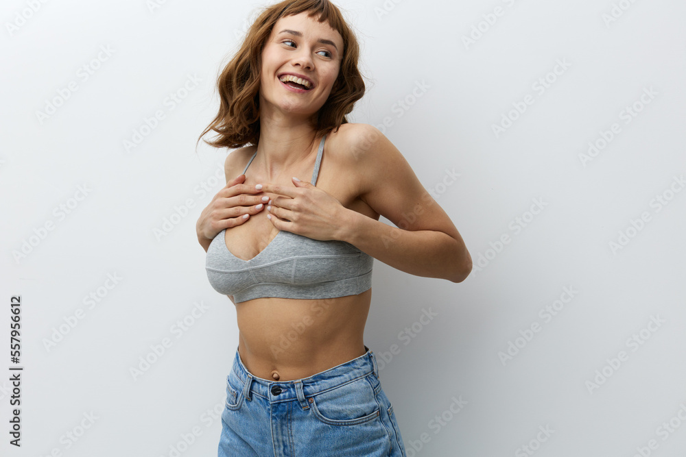 a happy, joyful woman stands on a bright background in stylish summer clothes and holds her hands on her chest, smiling broadly - obrazy, fototapety, plakaty 