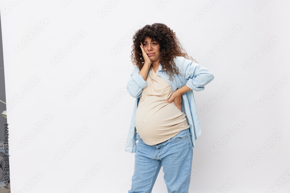 Pregnant woman tired, headache tears and frustration, difficult pregnancy, the last month before childbirth on a white isolated background in a T-shirt with a blue shirt Pregnant woman tired, headache tears and frustration, difficult pregnancy, the last month before childbirth on a white isolated background in a T-shirt with a blue shirt